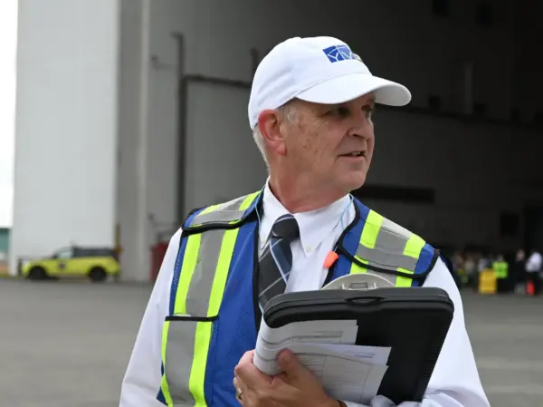 a man in a vest and hat holding a clipboard